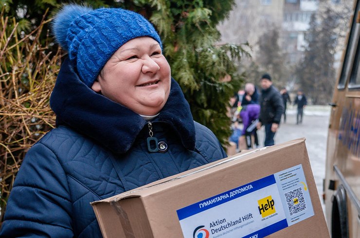 Eine lächelnde Ukrainerin mit hält ein Hilfspaket in der Hand